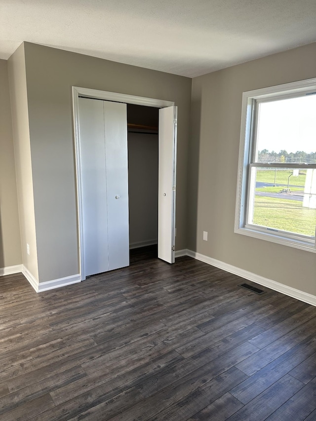 unfurnished bedroom with dark hardwood / wood-style flooring and a closet