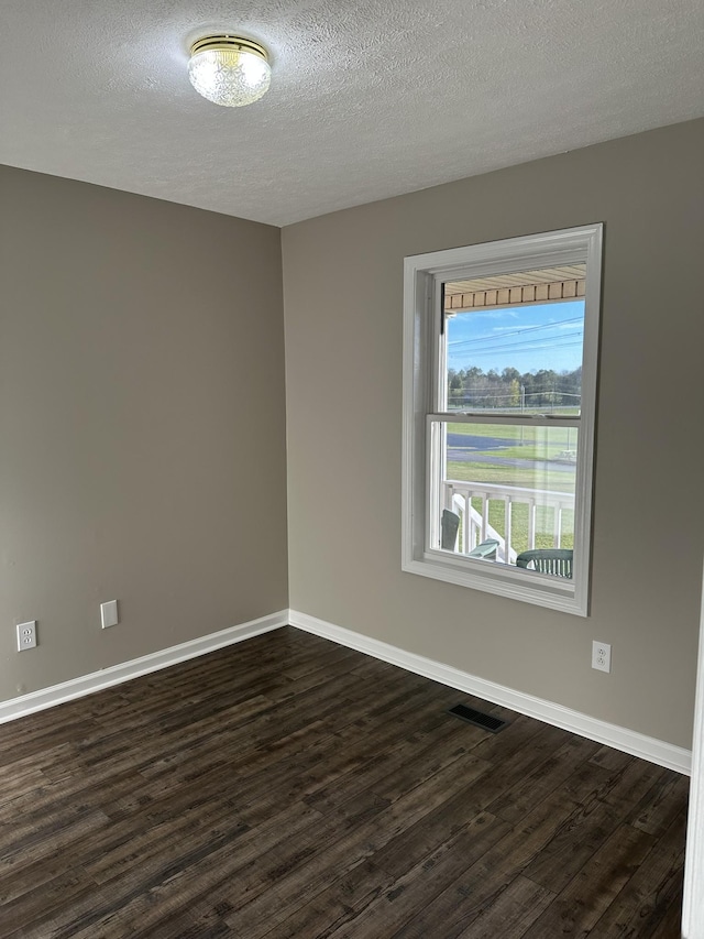 empty room featuring a textured ceiling and dark hardwood / wood-style flooring