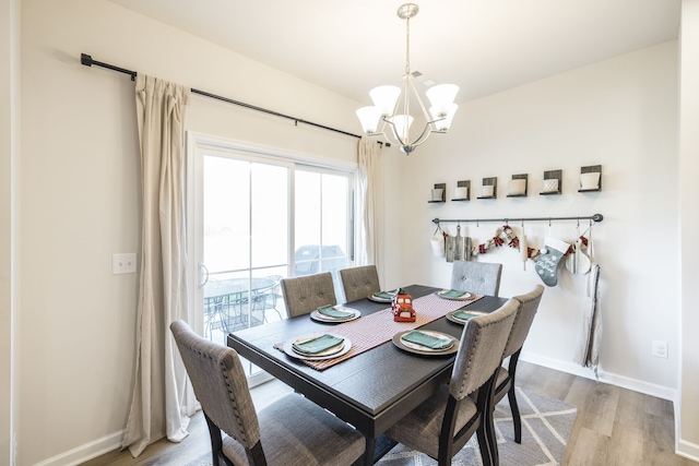 dining space with hardwood / wood-style floors and an inviting chandelier