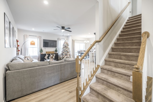 living room featuring plenty of natural light, wood-type flooring, and ceiling fan with notable chandelier