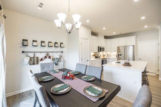 dining room with an inviting chandelier, light hardwood / wood-style flooring, and sink