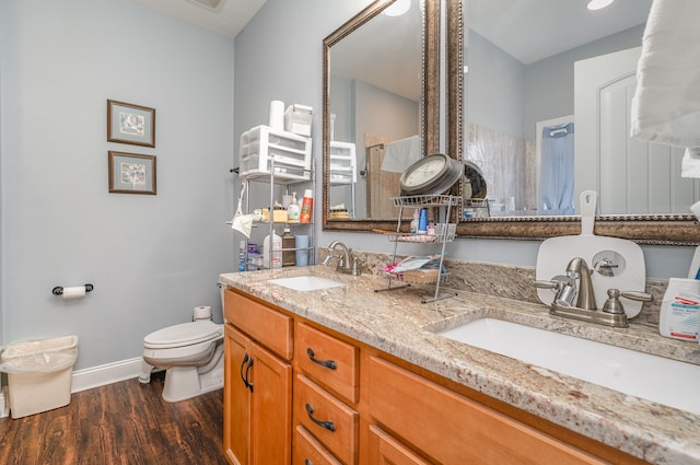 bathroom with hardwood / wood-style flooring, vanity, toilet, and a shower with shower door