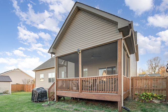 rear view of house with a sunroom and a yard