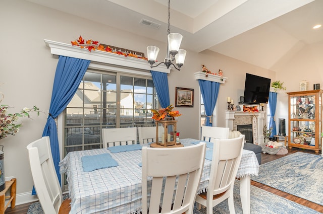 dining area with hardwood / wood-style floors, vaulted ceiling, and a chandelier