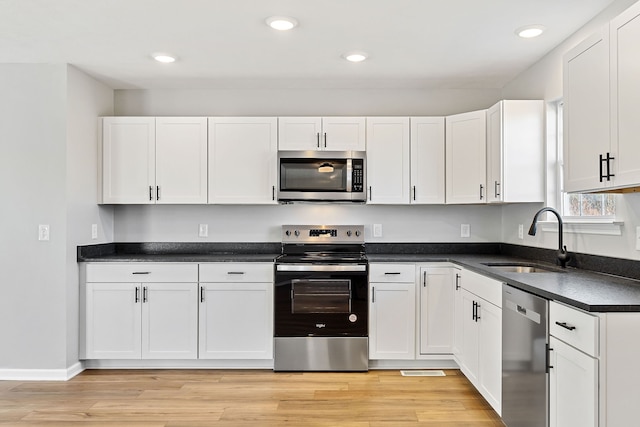 kitchen featuring white cabinets, appliances with stainless steel finishes, light wood-type flooring, and sink