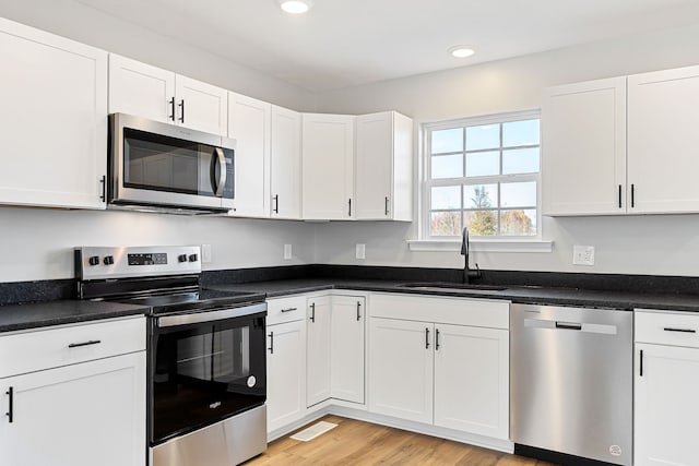 kitchen featuring sink, white cabinets, stainless steel appliances, and light wood-type flooring