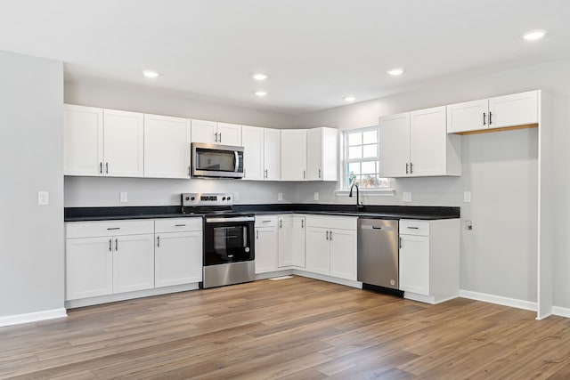 kitchen featuring white cabinets, appliances with stainless steel finishes, light wood-type flooring, and sink