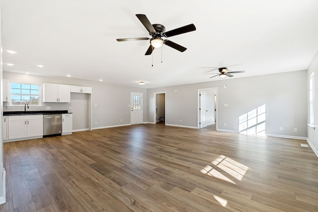 unfurnished living room with ceiling fan, sink, and wood-type flooring