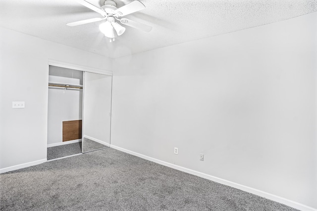 unfurnished bedroom featuring dark colored carpet, ceiling fan, a textured ceiling, and a closet