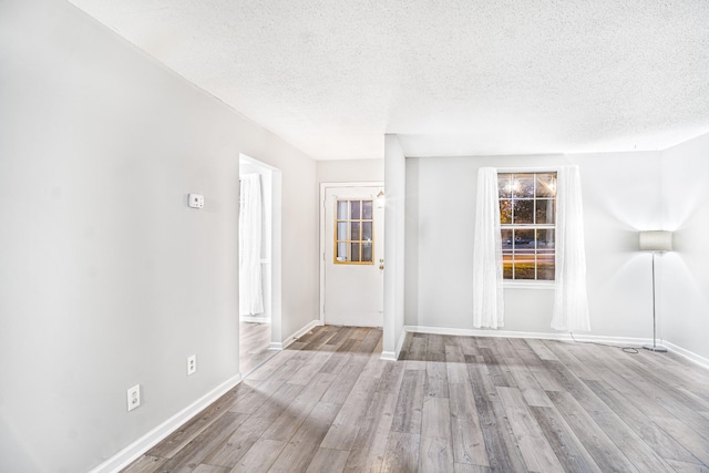 spare room featuring a textured ceiling and light hardwood / wood-style flooring