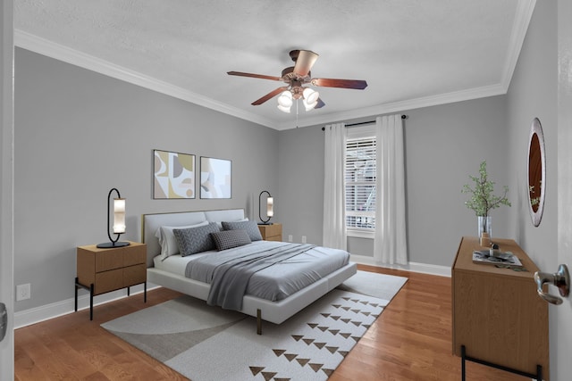 bedroom featuring a textured ceiling, light hardwood / wood-style flooring, ceiling fan, and crown molding