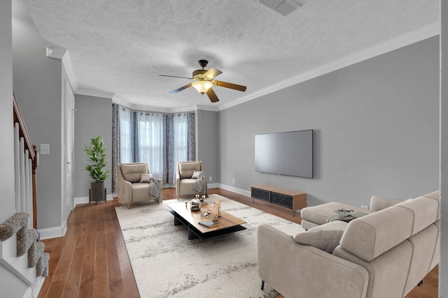 living room featuring a textured ceiling, hardwood / wood-style flooring, ceiling fan, and crown molding