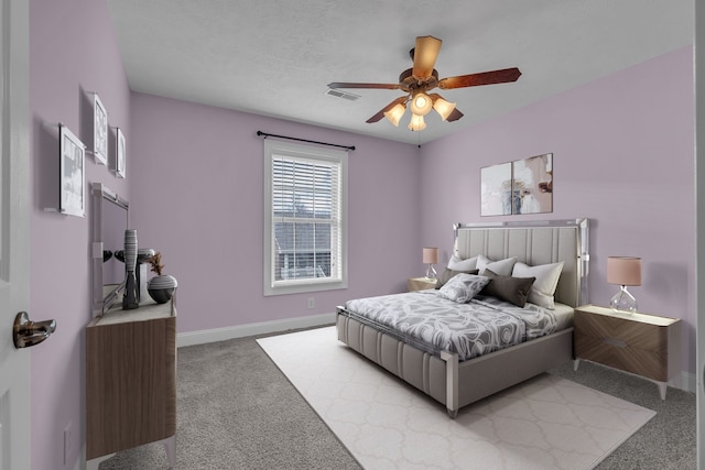 carpeted bedroom featuring ceiling fan and a textured ceiling