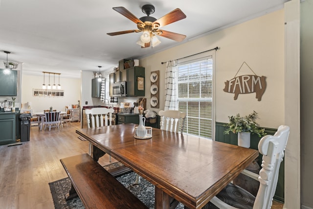 dining room with light wood-type flooring, ceiling fan, and sink