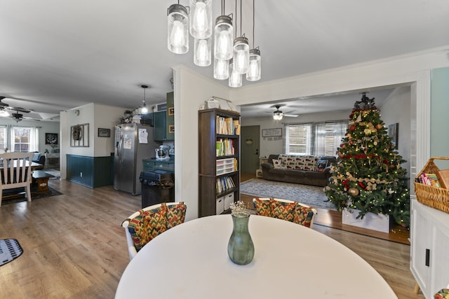 dining space featuring ceiling fan with notable chandelier, light wood-type flooring, and a wealth of natural light