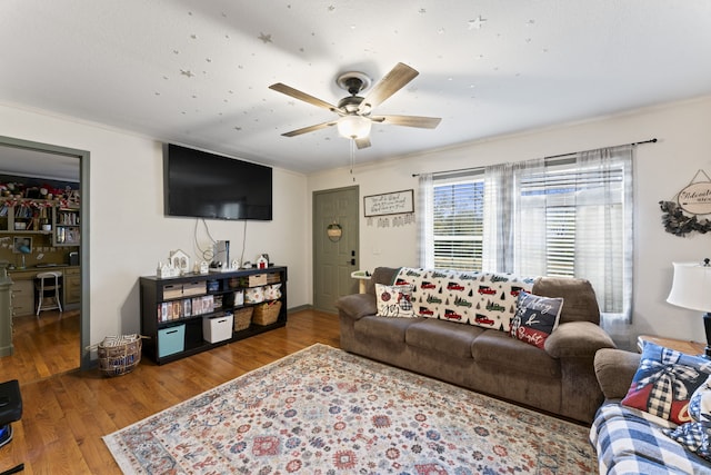 living room featuring hardwood / wood-style flooring, ceiling fan, and ornamental molding