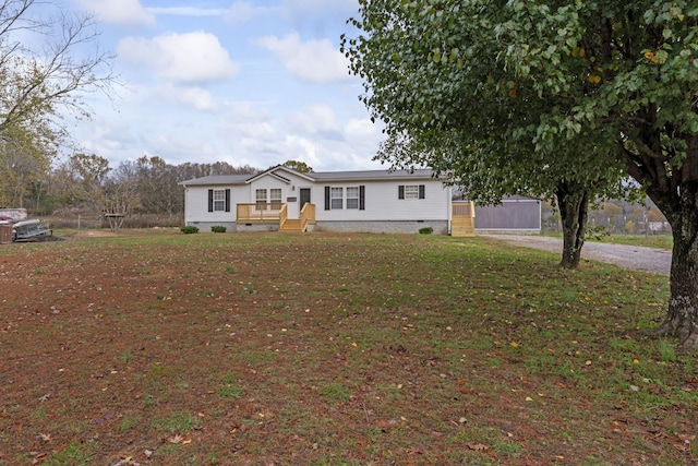 manufactured / mobile home with a front yard and a wooden deck