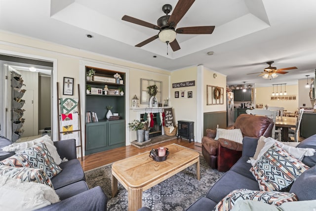 living room with hardwood / wood-style flooring, ceiling fan, and a raised ceiling