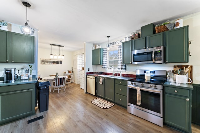 kitchen featuring appliances with stainless steel finishes, decorative light fixtures, and green cabinetry