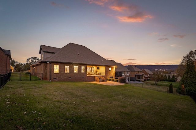 back house at dusk with a lawn