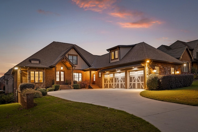 view of front of house with brick siding, a garage, a lawn, and driveway