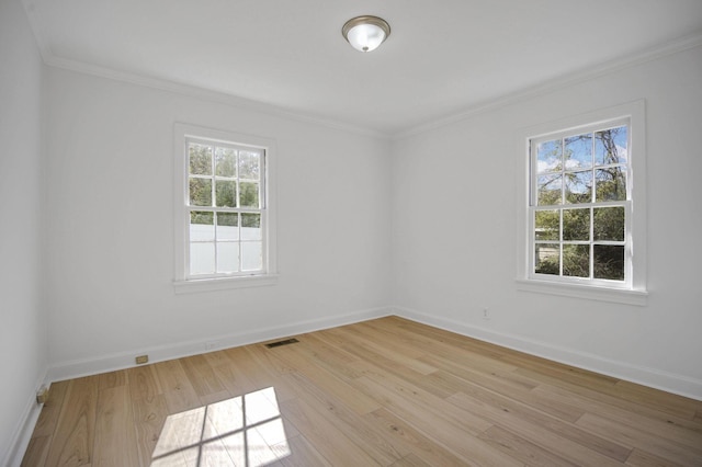 empty room featuring crown molding, a healthy amount of sunlight, and light hardwood / wood-style flooring