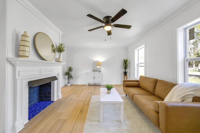 living room featuring light wood-type flooring, ornamental molding, ceiling fan, and a healthy amount of sunlight