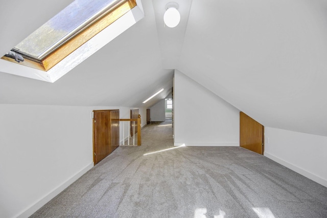 additional living space with vaulted ceiling with skylight, carpet, and a healthy amount of sunlight