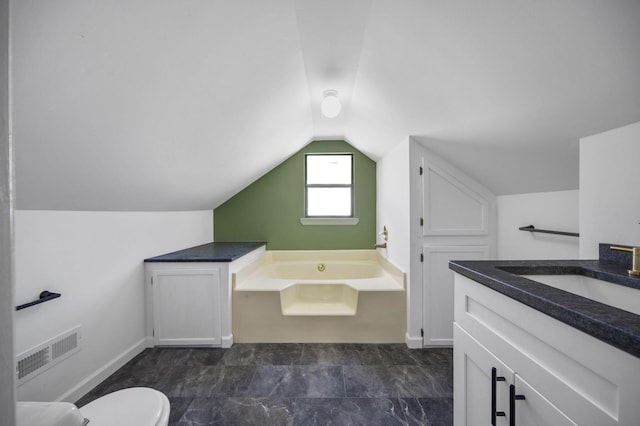 bathroom featuring vanity, toilet, a tub, and vaulted ceiling