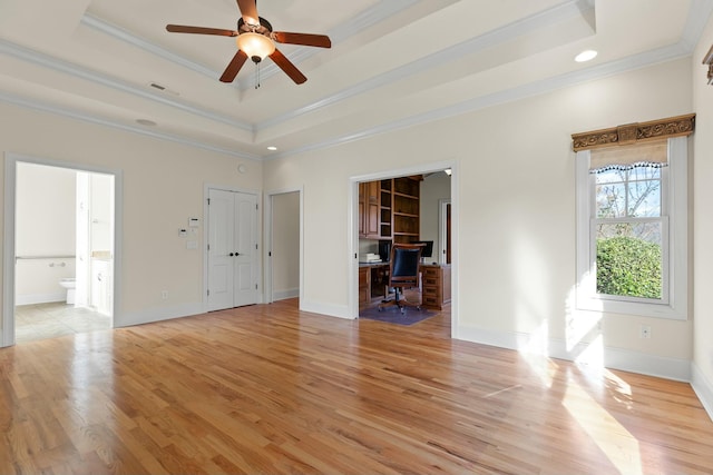 interior space with ceiling fan, a raised ceiling, crown molding, and light hardwood / wood-style flooring