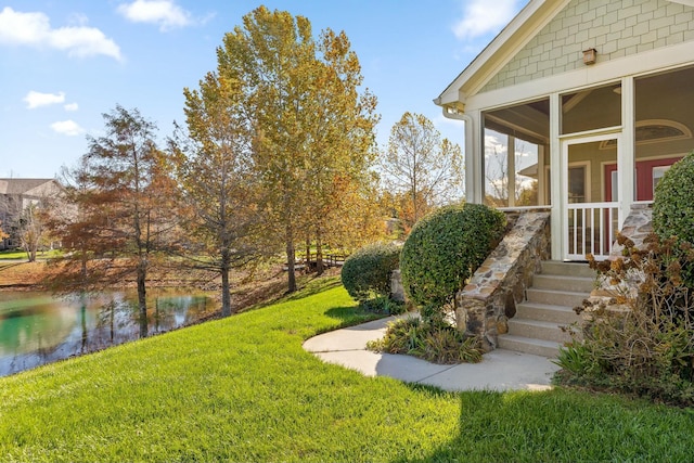 view of yard featuring a sunroom and a water view