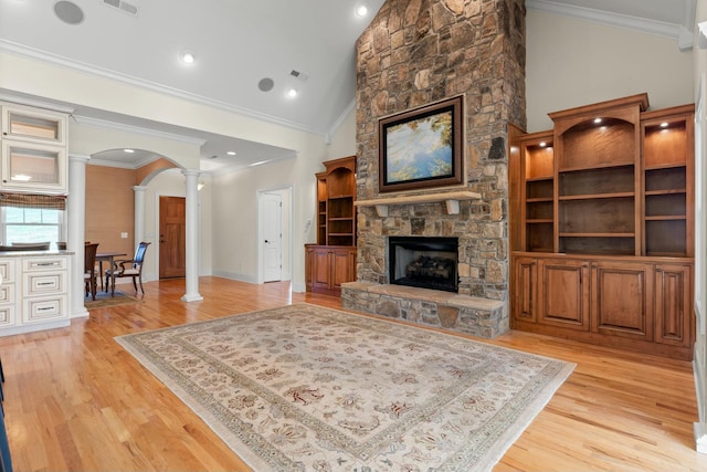 living room featuring decorative columns, a fireplace, light hardwood / wood-style floors, and ornamental molding