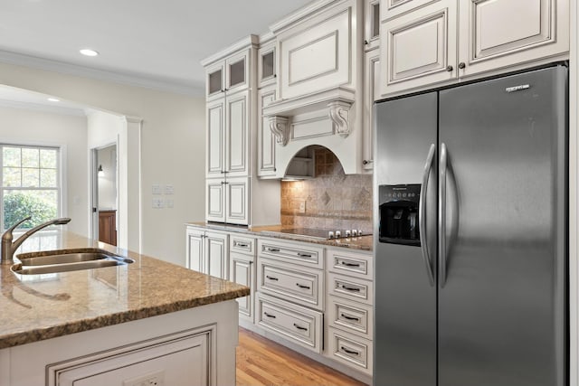 kitchen featuring stone counters, sink, ornamental molding, black electric cooktop, and stainless steel fridge with ice dispenser