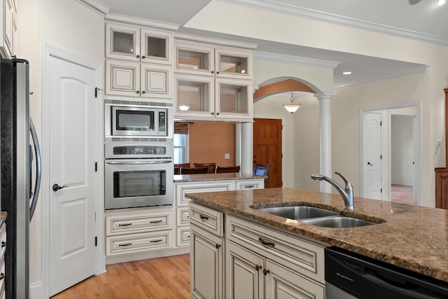 kitchen featuring dark stone counters, sink, light hardwood / wood-style flooring, ornate columns, and stainless steel appliances