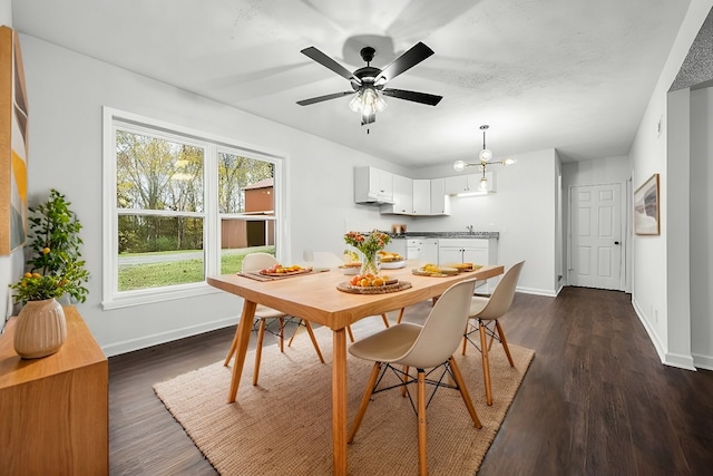 dining room featuring dark wood finished floors, ceiling fan with notable chandelier, and baseboards