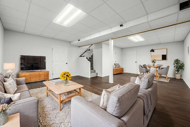 living room with stairway, a paneled ceiling, baseboards, and wood finished floors