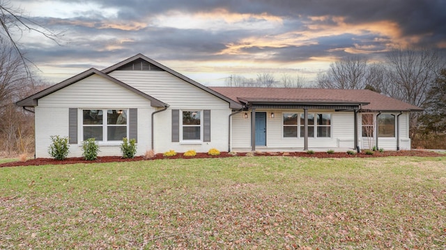 ranch-style home with brick siding, covered porch, a shingled roof, and a front yard