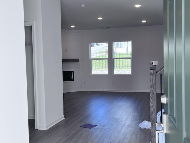 unfurnished living room featuring a large fireplace and dark wood-type flooring