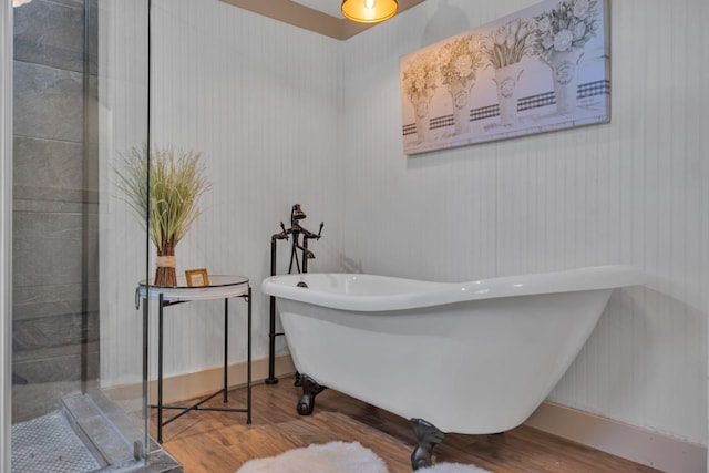 bathroom featuring hardwood / wood-style floors, a bathtub, and wooden walls