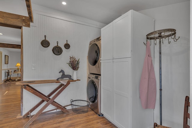 laundry area with stacked washer and dryer and light wood-type flooring