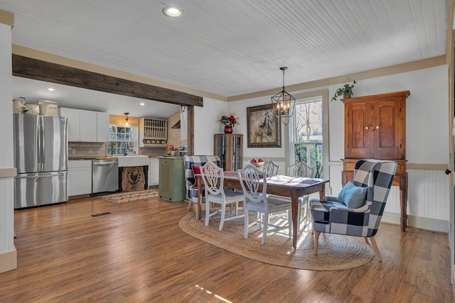 dining space with hardwood / wood-style floors, a notable chandelier, and a healthy amount of sunlight