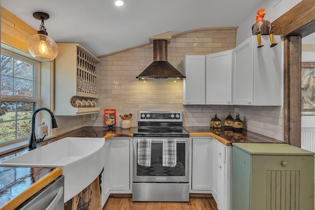 kitchen with white cabinets, wall chimney range hood, sink, appliances with stainless steel finishes, and decorative light fixtures