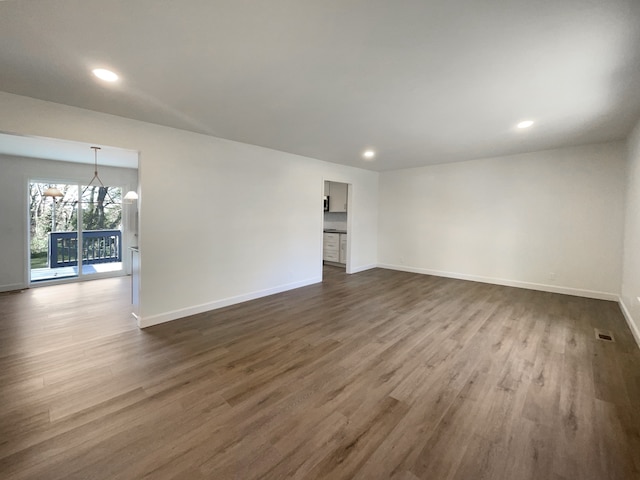 empty room with dark wood-type flooring and an inviting chandelier