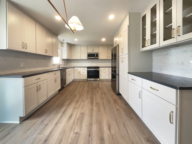 kitchen featuring white cabinetry, hanging light fixtures, wood-type flooring, and appliances with stainless steel finishes