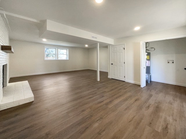 basement with a fireplace and dark wood-type flooring