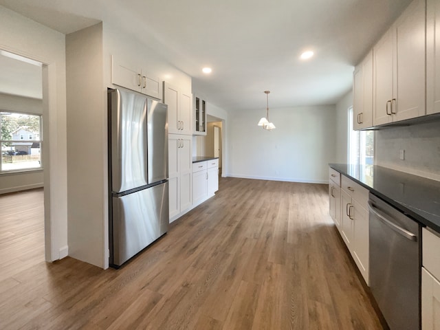 kitchen with white cabinetry, stainless steel appliances, wood-type flooring, decorative light fixtures, and decorative backsplash