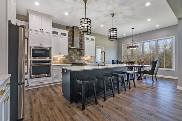 kitchen featuring white cabinetry, sink, dark wood-type flooring, stainless steel appliances, and a center island with sink