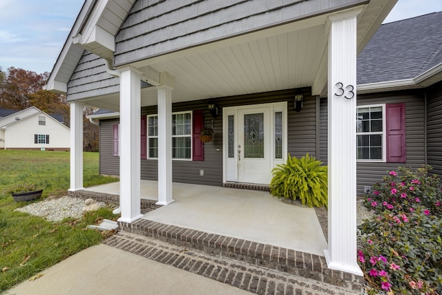 entrance to property featuring a yard and covered porch