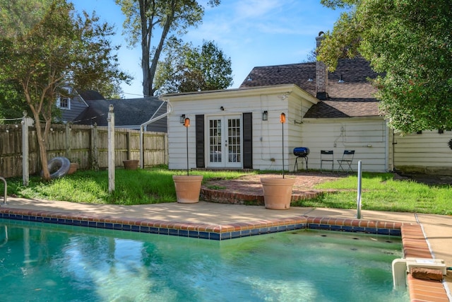 back of property with a fenced in pool and an outbuilding