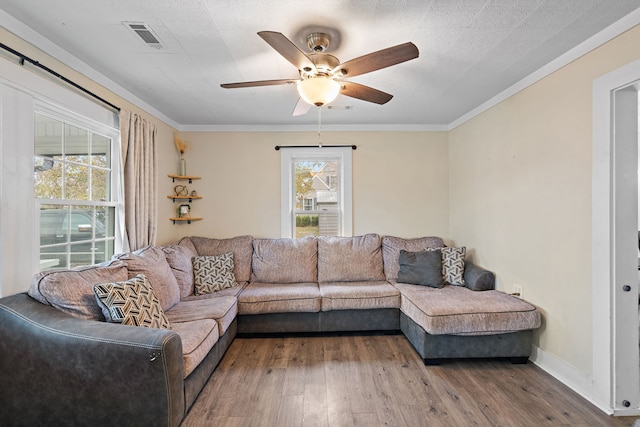 living room featuring a textured ceiling, ceiling fan, wood-type flooring, and ornamental molding